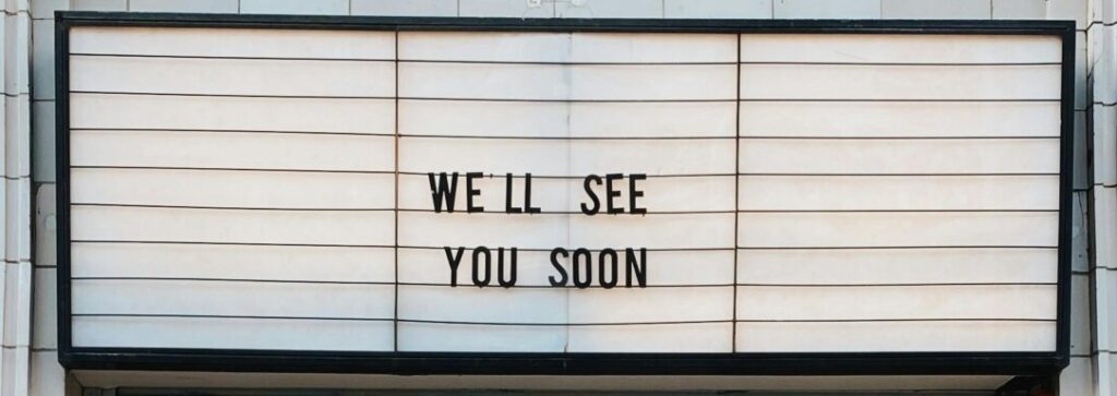 Street view of a bicycle against a London building with a sign reading 'We'll See You Soon.'